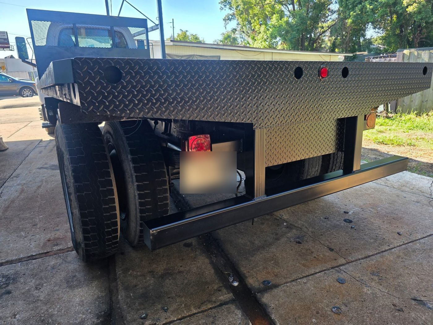 Flatbed truck with diamond-plate deck and rear fabrication